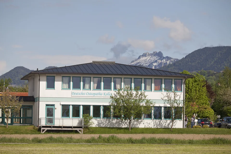 Das Gebäude des Deutschen Osteopathie Kollegs, dahinter die Berge